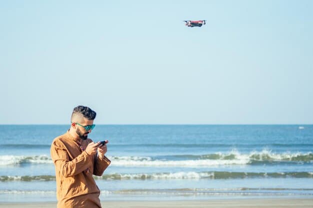 A close-up shot of a lifeguard using a drone to monitor the beach. The drone is equipped with a camera and is hovering above the water, providing a bird's-eye view of the swimming area. In the background, people are enjoying the beach.