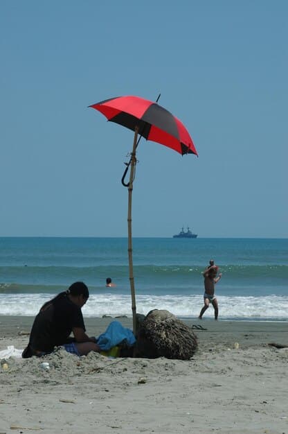 A beach umbrella firmly anchored in the sand using a sand anchor tool, showing how it provides additional stability against strong winds.
