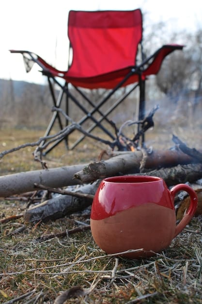 A close-up photograph of a campsite on a beach, showing a tent, a small campfire, and camping chairs. The scene has a cozy and inviting feel, perfect for a camping trip.