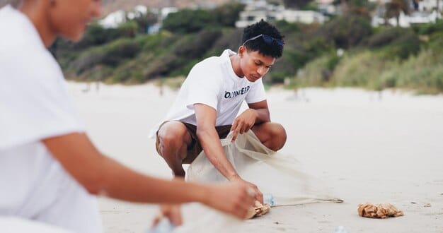 A close-up shot of a person picking up trash on a beach, with a focus on their hand and the trash they're collecting. The background shows other beachgoers enjoying the beach, subtly emphasizing the importance of keeping the beach clean.