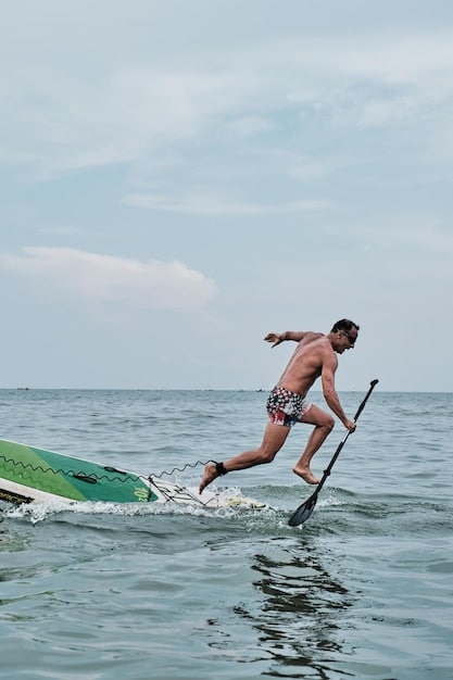Action shot of a person participating in a stand-up paddleboard race, demonstrating speed, balance, and athletic ability. The paddler is intensely focused, and the water is splashing around the board.