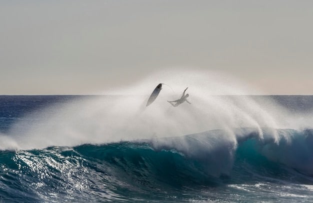 A surfer riding a large, breaking wave. The wave is powerful and dynamic, with white foam cresting at the top. The surfer is skillfully maneuvering through the wave, demonstrating control and expertise.