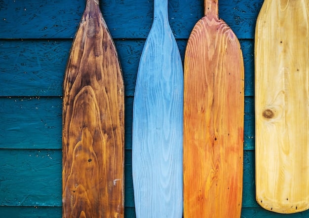 A close-up of different types of beginner surfboards stacked on a beach, highlighting the differences in size and material (foam vs. hard top).