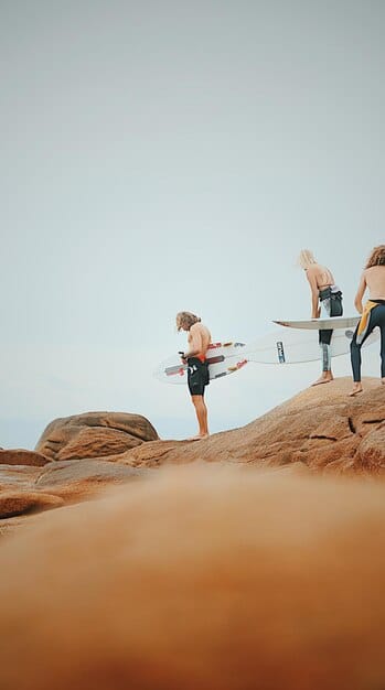 A series of four images showing the step-by-step process of a surfer practicing the pop-up technique on land.