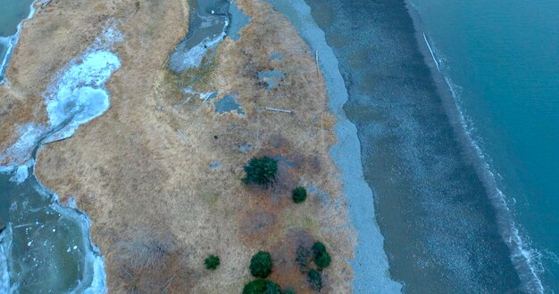 An aerial view of a coastal city with parts of its shoreline submerged due to sea-level rise. The image should show the contrast between the developed area and the encroaching sea, highlighting the vulnerability of coastal infrastructure. The sky should be overcast to emphasize the somber mood.