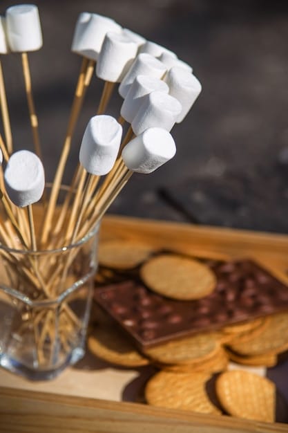 A close-up shot of a gourmet s'mores station at a luxury beach bonfire. The ingredients are beautifully arranged with artisanal marshmallows, gourmet chocolates, and freshly baked graham crackers. Soft lighting highlights the rich colors and textures.