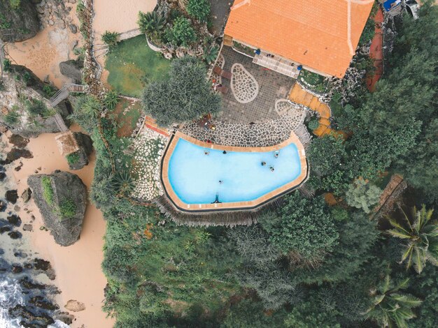 An aerial view of a luxury beach resort showcasing its water treatment facilities and organic gardens. The resort blends seamlessly into the surrounding green landscape, emphasizing its commitment to environmental preservation.