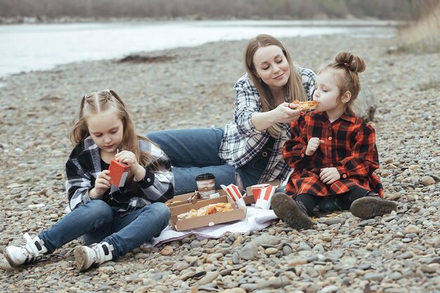 A family enjoying a picnic lunch on a beach blanket, with homemade sandwiches and refreshing drinks, emphasizing the cost savings of preparing your own meals.