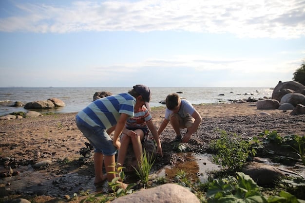 A group of volunteers planting dune grass on a beach. They are working together, smiling, and enjoying the sunshine. The ocean and blue sky are visible in the background.