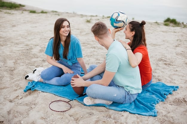 A group of friends laughing and comparing their finds on a beach, with various shells, sea glass, and pebbles scattered on a towel.