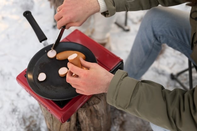 A compact, portable camping stove being used to cook a simple meal on a folding table at a beach campsite, with cooking utensils and ingredients neatly arranged, highlighting efficient meal preparation.