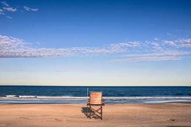 A serene shot of a pristine, uncrowded beach in Florida, with gentle waves lapping at the shore and a single, elegant beach chair awaiting a guest under a clear blue sky.