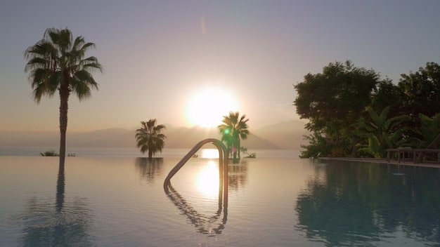 A luxurious infinity pool overlooking the Pacific Ocean at sunset, with a silhouette of palm trees and elegant loungers, emphasizing serenity and high-end comfort.