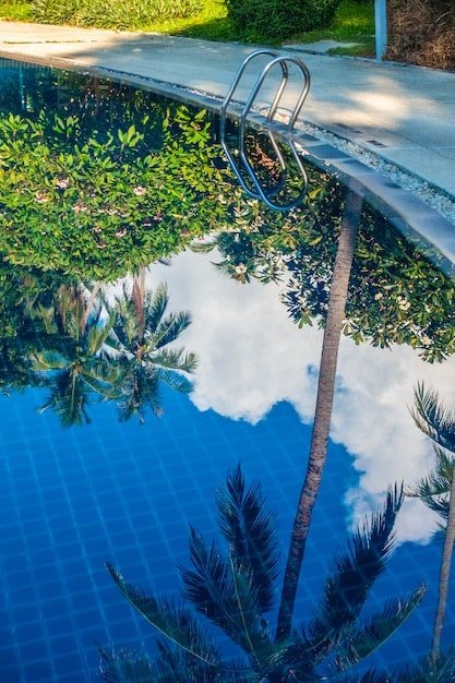 A serene luxury resort pool area with lush, native landscaping, visible sustainable water features, and solar panels subtly integrated into the roofline of a distant building.