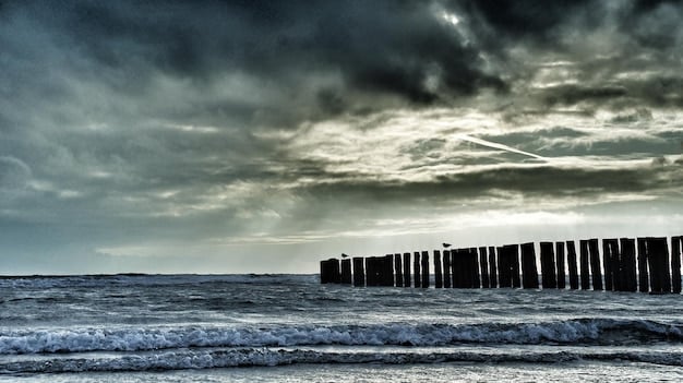 A dark, stormy sky over a beach with rough waves, a warning flag flying, and a few distant figures hurrying away from the shore.